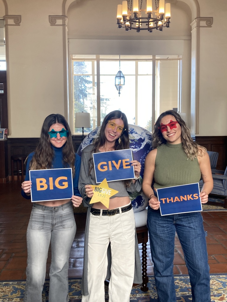 Residents holding Big Give signs by our globe
