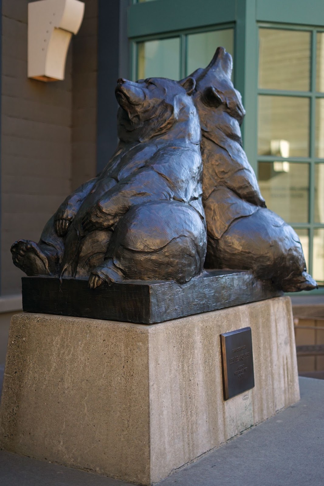 A statue of two bears, back to back, facing up, and slumped on each other. 