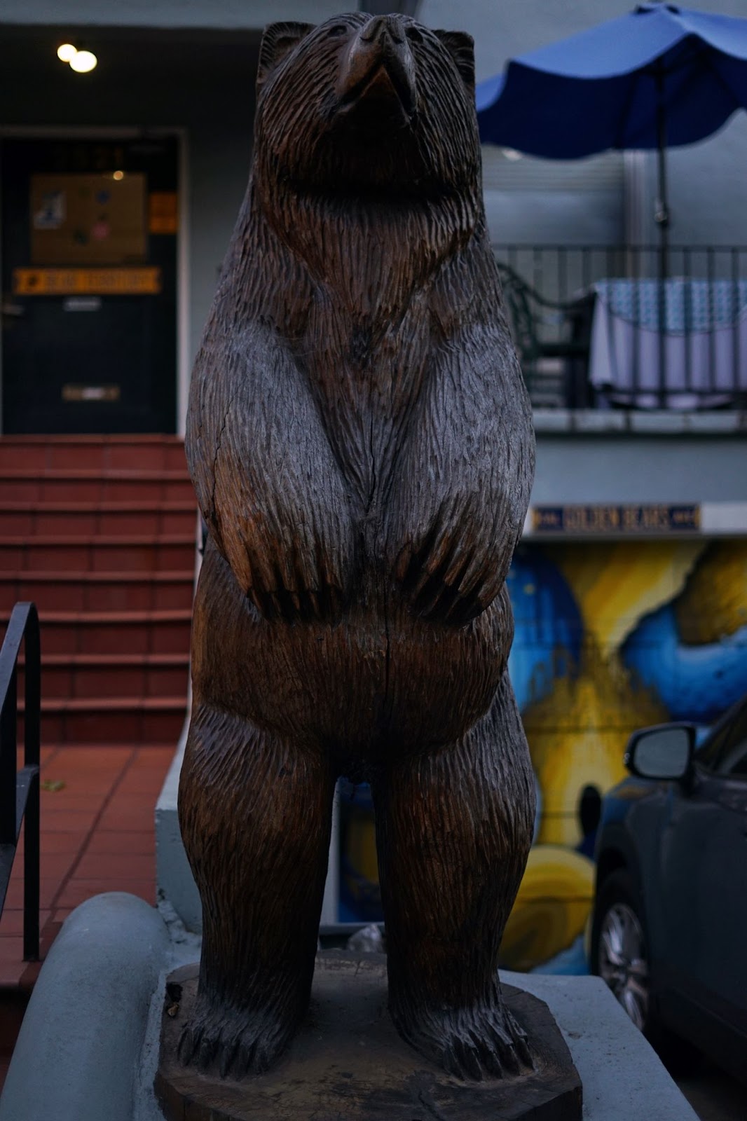 A wood carved statue of a bear standing upright. 