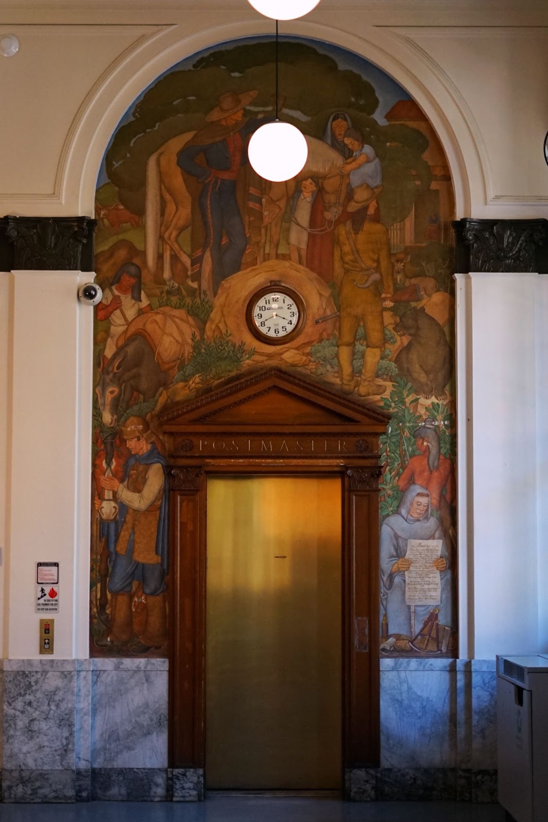 A detailed mural over the wall above an elevator. It depicts a complex scene. There is one bear on the right side. 