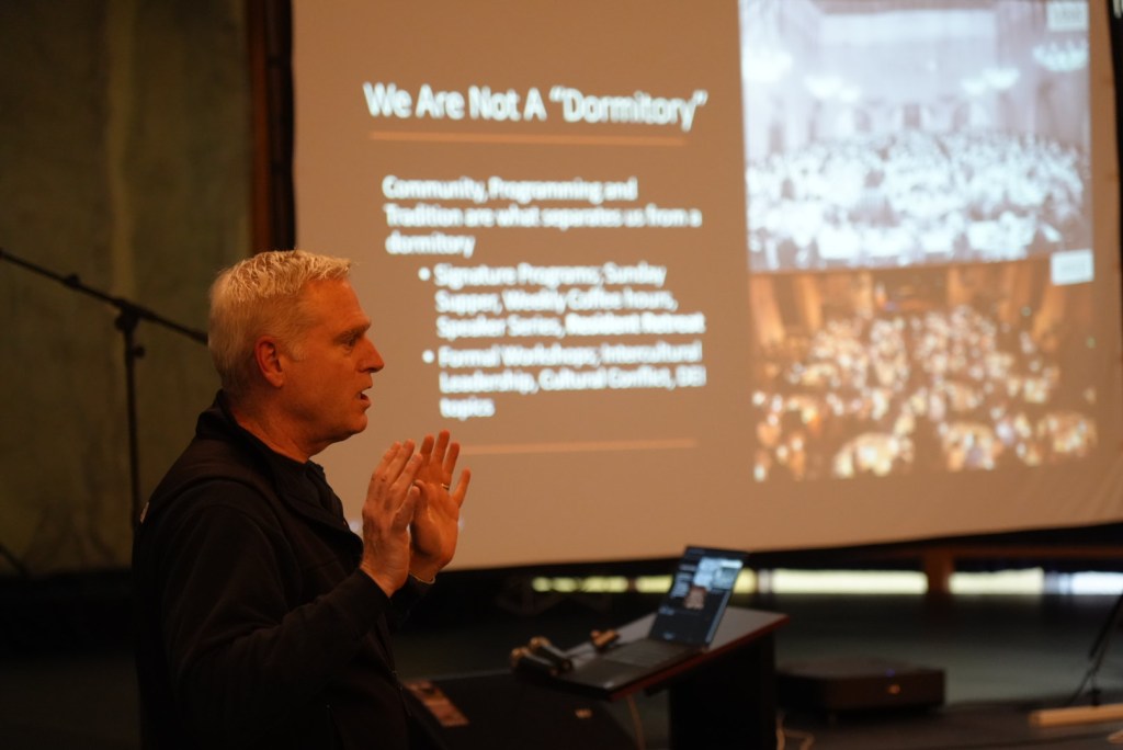 Shawn Carver, the I-House Berkeley Executive Director presenting. The slide behind him shows the topic "We are not a "Dormitory". 