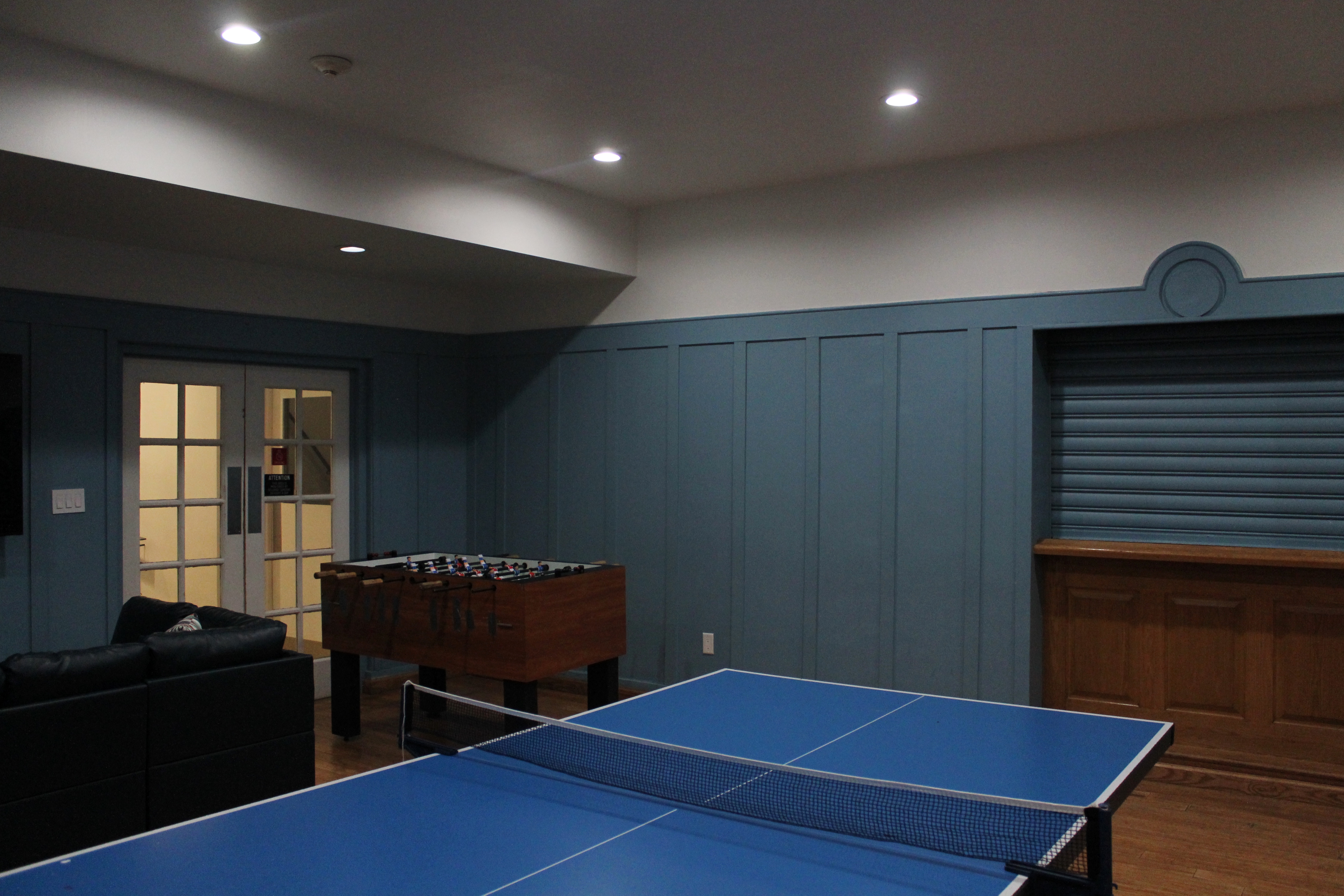 A game room with blue wood-panelled walls and a foosball table. 