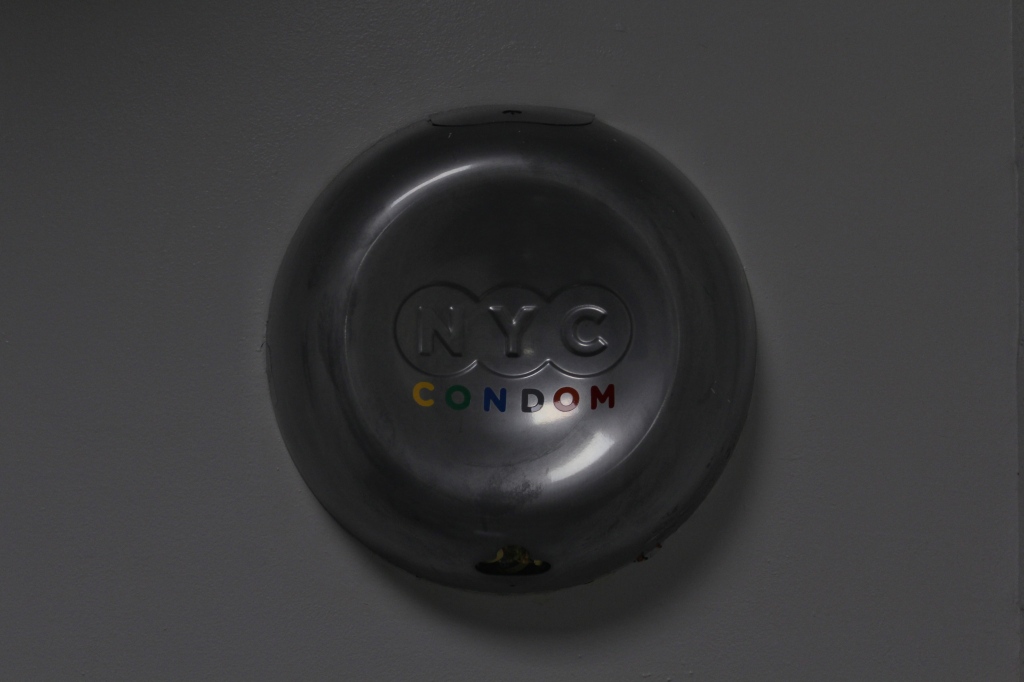 A condom dispenser reads "NYC CONDOM"
