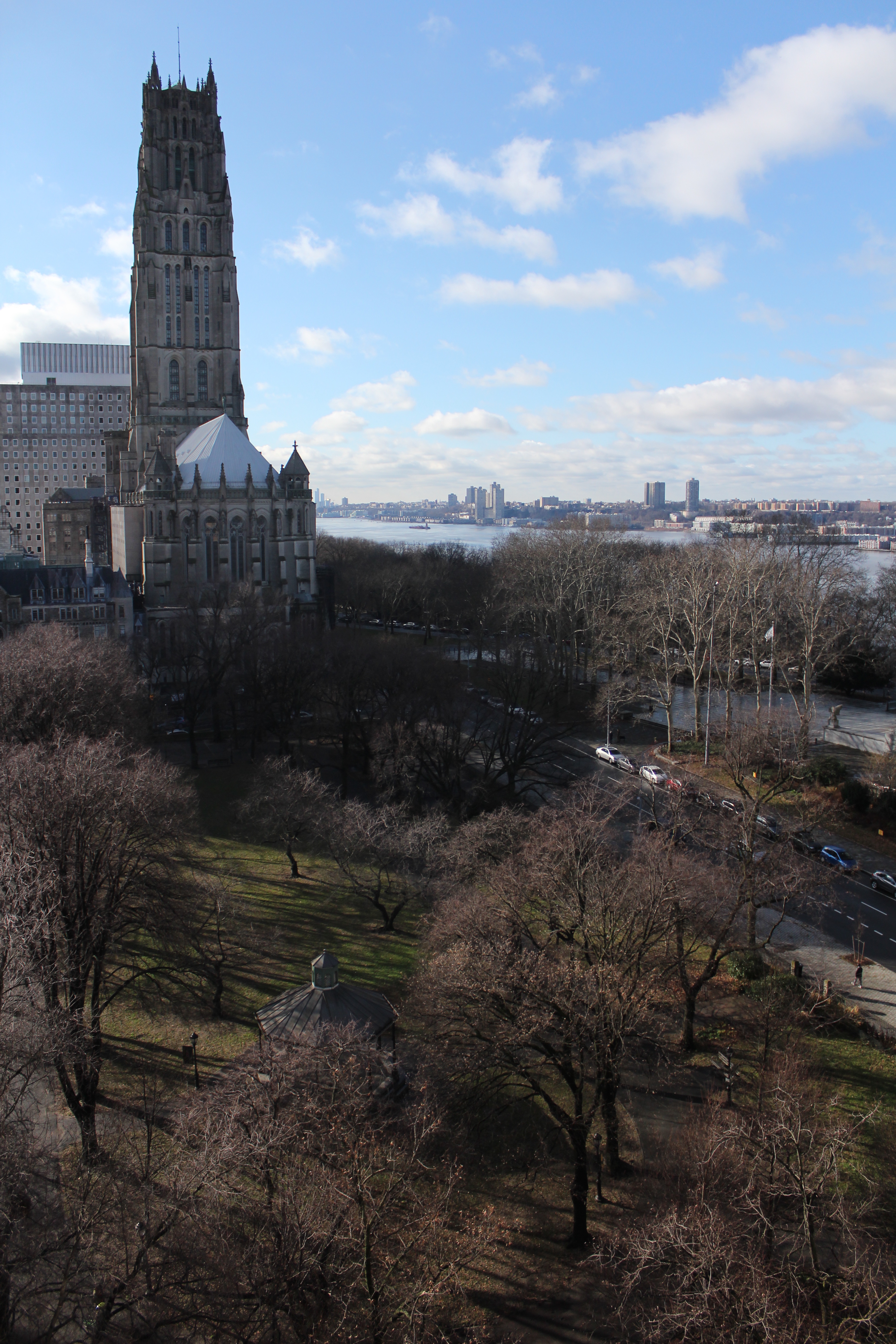 A view of a church and a park with barren trees with a river in the backdrop.