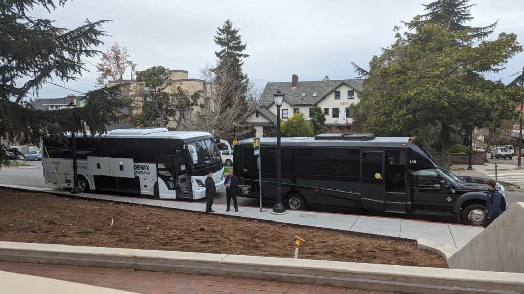 Buses for transporting residents to the retreat lined up in from on the international house ready to set off. 