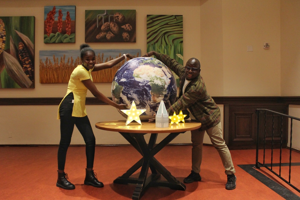 Two residents hold a globe on a table adorned with Big Give themed decor.